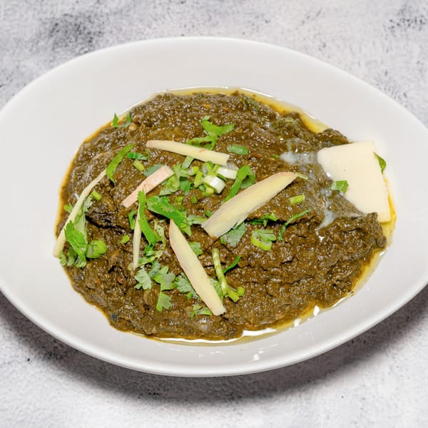 Indian Saag Paneer, a creamy spinach dish with paneer cheese, garnished with ginger and cilantro.