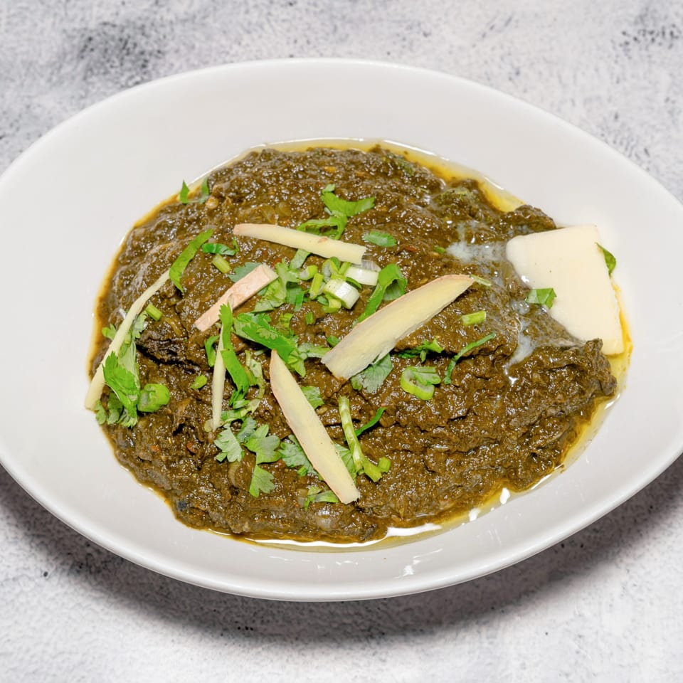 Indian Saag Paneer, a creamy spinach dish with paneer cheese, garnished with ginger and cilantro.